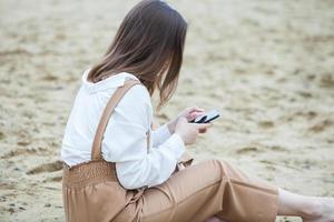 Girl outdoors texting on her mobile phone. Girl with phone. Portrait of a happy woman text sms message on her phone. photo