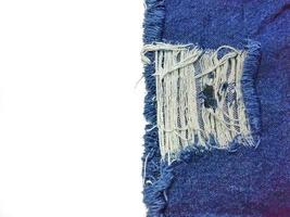 la textura de los jeans azules tiene una lágrima, vea la tela blanca en el interior. dando una nueva perspectiva que nunca se ha visto espacio de copia de fondo blanco foto