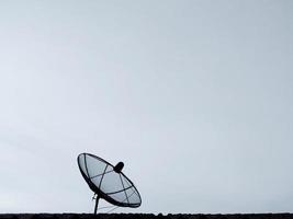 black satellite dish on the roof of the house  overcast sky  On a day with inclement weather photo