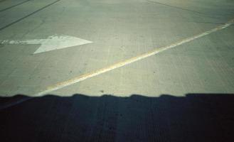 The black shadow on concrete with a white arrow pointing to the right, giving the idea of direction. photo