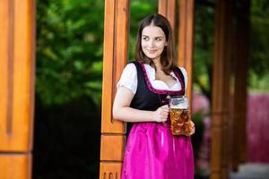 mujer rusa sexy con vestido bávaro sosteniendo jarras de cerveza. foto