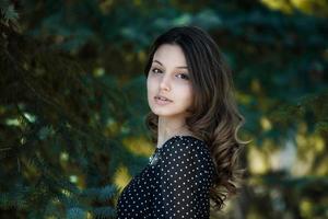 Woman's portrait with a hair moving in the wind. Close-up portrait of young beautiful Russian brunette girl at summer green park. European white woman in dress. photo