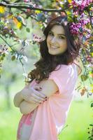 hermosa chica europea blanca con piel limpia en el parque con árboles en flor foto