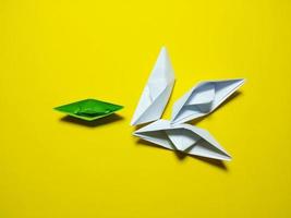 falling green white paper boat The yellow background gives the concept of leadership and ineffective management. causing failure to feel broken, unsuccessful, selfish photo
