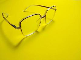 Eyeglasses on yellow background copy space. Gives the concept of wearing eye protection glasses in summer photo