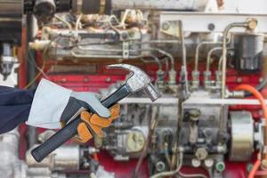 Hand in glove holding hammer with engine photo