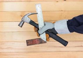 Hand in glove holding iron ruler and hammer photo