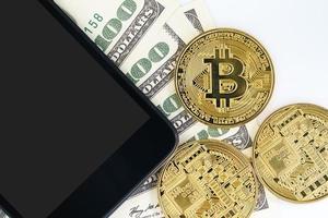 Top view Bitcoins coin and  US banknotes of one hundred dollars with smartphone photo