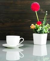 taza de café y ramo de flores artificiales sobre la mesa foto