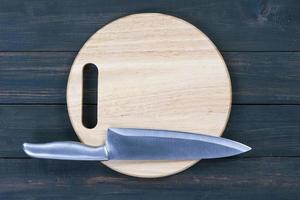 Kitchen knife on wooden round cutting board close up photo