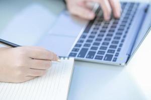 Woman working at home office using laptop searching web, browsing information photo