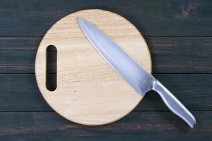 Close up kitchen knife on wooden round cutting board photo