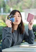 Young woman sitting showing passport and credit card photo