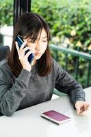 woman sitting and using smartphone for online shopping with credit card and passport on deck in home office photo