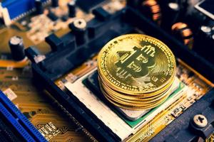 Stack of golden coins with bitcoin symbol on a mainboard. photo