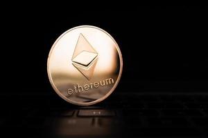 A golden coin with ethereum symbol on computer keyboard. photo