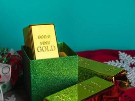 Gold bars as christmas present on wooden table with ornaments. photo