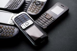 Old and obsoleted cellphones on a black background. photo
