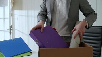 Businessman put things and documents on his desk into the paper box. photo