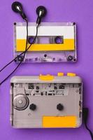 Cassette player with earphones and cassette tape on purple background. photo