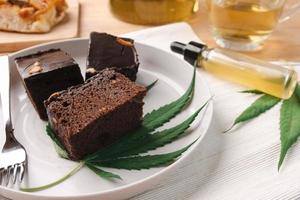 Homemade sweetmeat with marijuana or cannabis leaf on white plate. Alternative medicine concept. photo