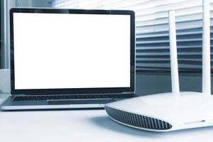 computadora portátil con pantalla en blanco y dispositivo de enrutador en la mesa foto