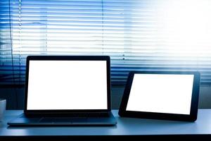 computadora portátil de pantalla en blanco y tableta en la mesa foto