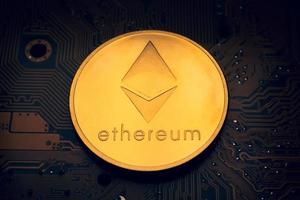 A golden coin with ethereum symbol on a mainboard. photo