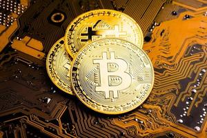 Golden coins with bitcoin symbol on a mainboard. photo