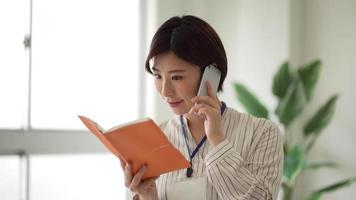 A female employee who opens a notebook while talking on the phone video