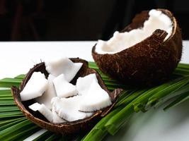 carne de coco y hoja de coco sobre mesa blanca. foto