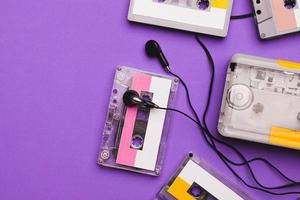 Cassette player with earphones and cassette tapes on purple background. photo