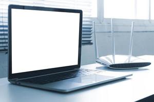 Blank screen laptop computer and router device on the table photo