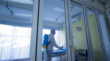 trabajador en equipo de protección personal traje de limpieza en edificio con agua desinfectante en aerosol para eliminar covid 19 foto