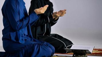 Two Asian Muslim young women in traditional hijab are praying glorify Allah and practicing the Islamic faith in mosque. photo