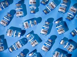 Glass vials for Covid-19 vaccine on blue background. Group of Coronavirus vaccine bottles. photo