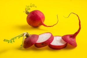 Red ripe sliced radish on yellow background photo