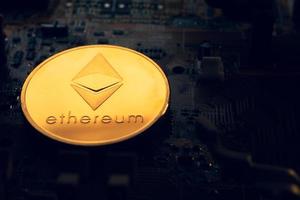 A golden coin with ethereum symbol on a mainboard. photo