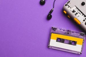 Cassette player with earphones and cassette tape on purple background. Copy space for text. photo