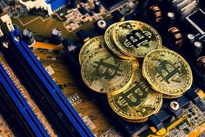 Golden coins with bitcoin symbol on a mainboard. photo