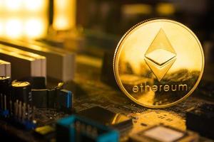 A golden coin with ethereum symbol on a mainboard. photo