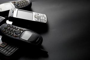 teléfonos celulares viejos y obsoletos en un fondo negro. foto