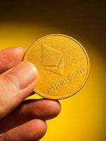 Hand holding golden coin with ethereum symbol.  Digital currency concept. photo