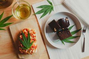 Food and drink and cannabis leaves on the dining table. Alternative medicine concept. photo