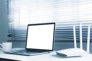 Blank screen laptop computer and router device on the table photo