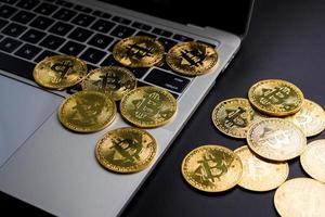 monedas de oro con el símbolo de bitcoin en el teclado de la computadora y un fondo negro. foto