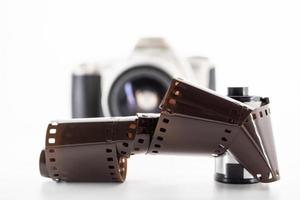 cámara réflex de lente única y un rollo de película sobre un fondo blanco. foto