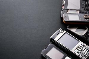 Old and obsoleted cellphones on a black background. photo