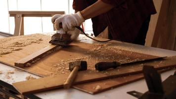 Carpenter using electric planer to shaving board at site. photo