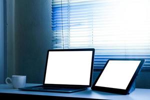 computadora portátil de pantalla en blanco y tableta en la mesa foto